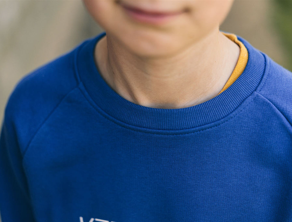 Close-up van een blauwe trui met opdruk KZENTMUUG.