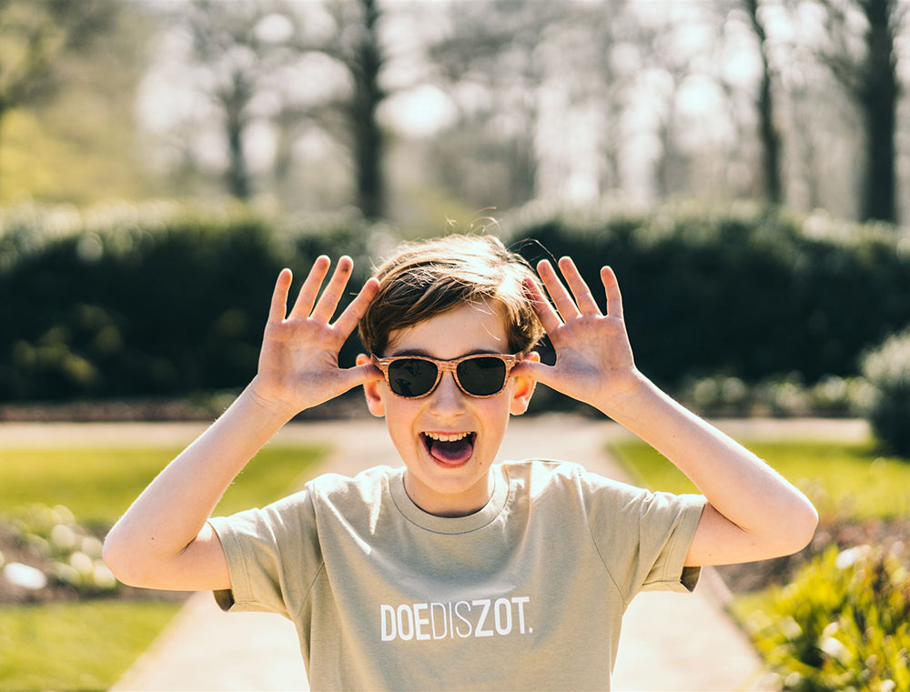 Jongen met een sage T-shirt met opdruk DOEDISZOT.