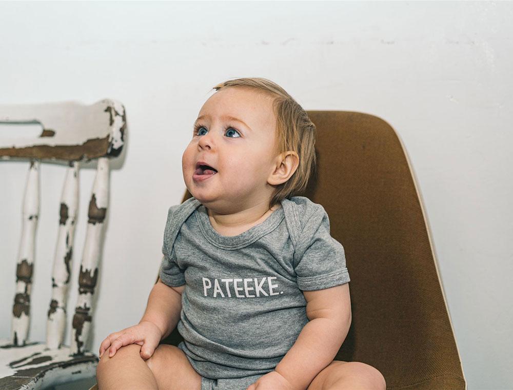 Baby met grijs rompertje met opdruk PATEEKE.