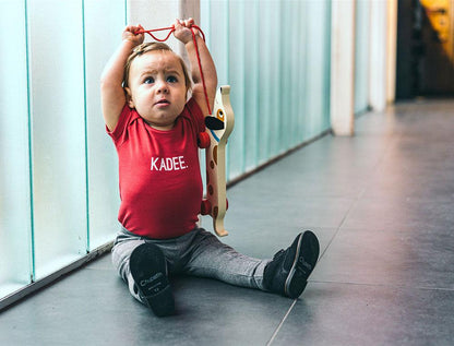 Baby met rood rompertje met opdruk KADEE.