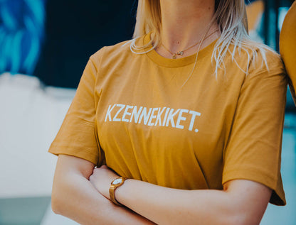 Vrouw met oker-kleurige T-shirt met opdruk KZENNEKIKET.