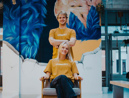 Man en vrouw met oker-kleurige T-shirt met opdruk KZENNEKIKET.