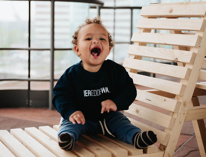 Baby met een blauwe trui voor baby's met opdruk IEREDDEWA.