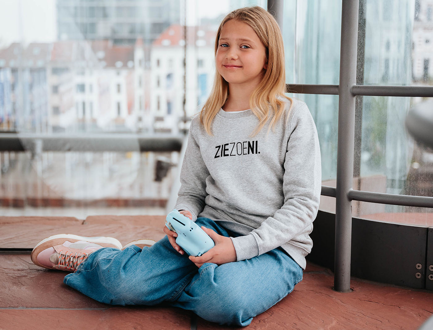 Meisje met een grijze trui voor kinderen met opdruk ZIEZOENI.