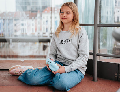 Meisje met een grijze trui voor kinderen met opdruk ZIEZOENI.