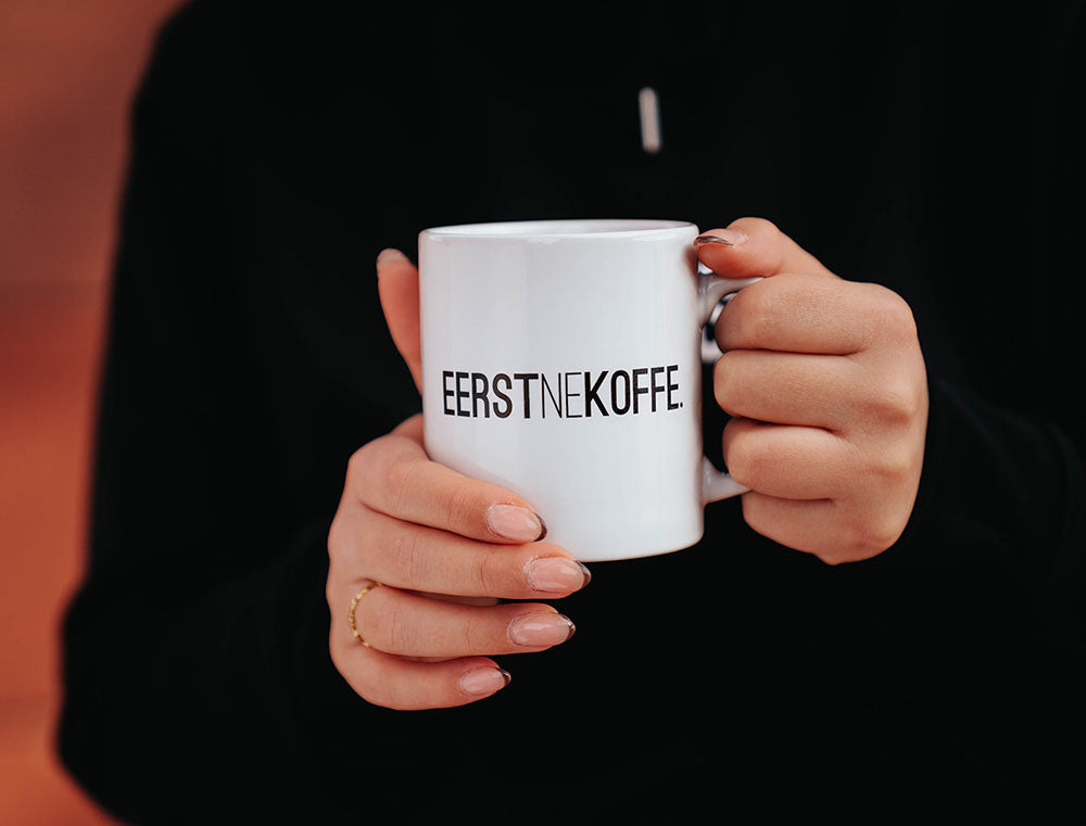 Een witte tas met opdruk EERSTNEKOFFE.