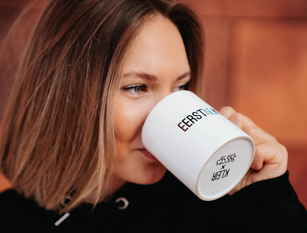 Vrouw met een een witte tas met opdruk EERSTNEKOFFE.