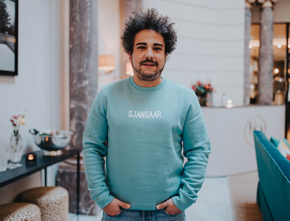 Man met een blauw-groene trui met opdruk SJANSAAR.