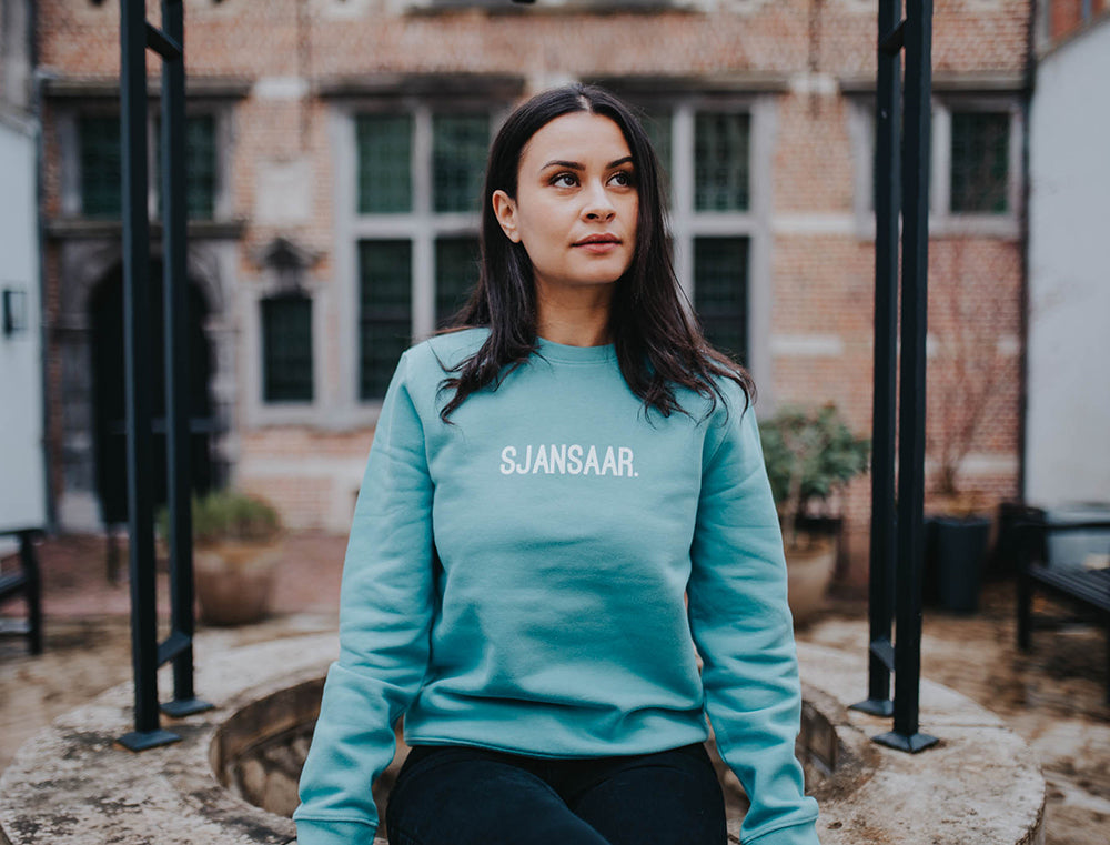 Vrouw met een blauw-groene trui met opdruk SJANSAAR.