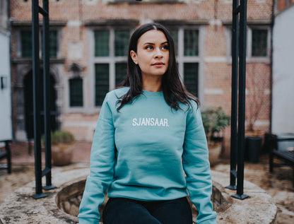Vrouw met een blauw-groene trui met opdruk SJANSAAR.