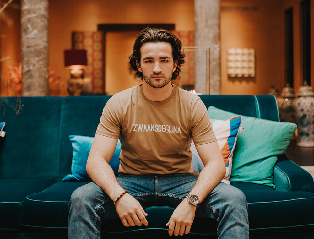 Man met een bruine T-shirt met opdruk ZWAANSDEGIJNA.