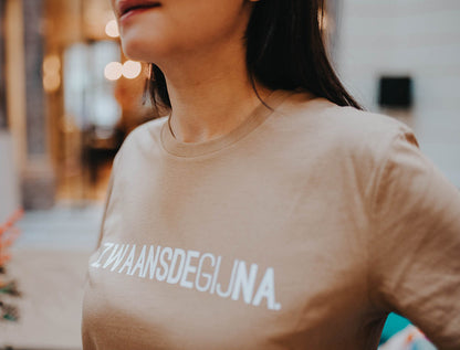 Close-up van een bruine T-shirt met opdruk ZWAANSDEGIJNA.