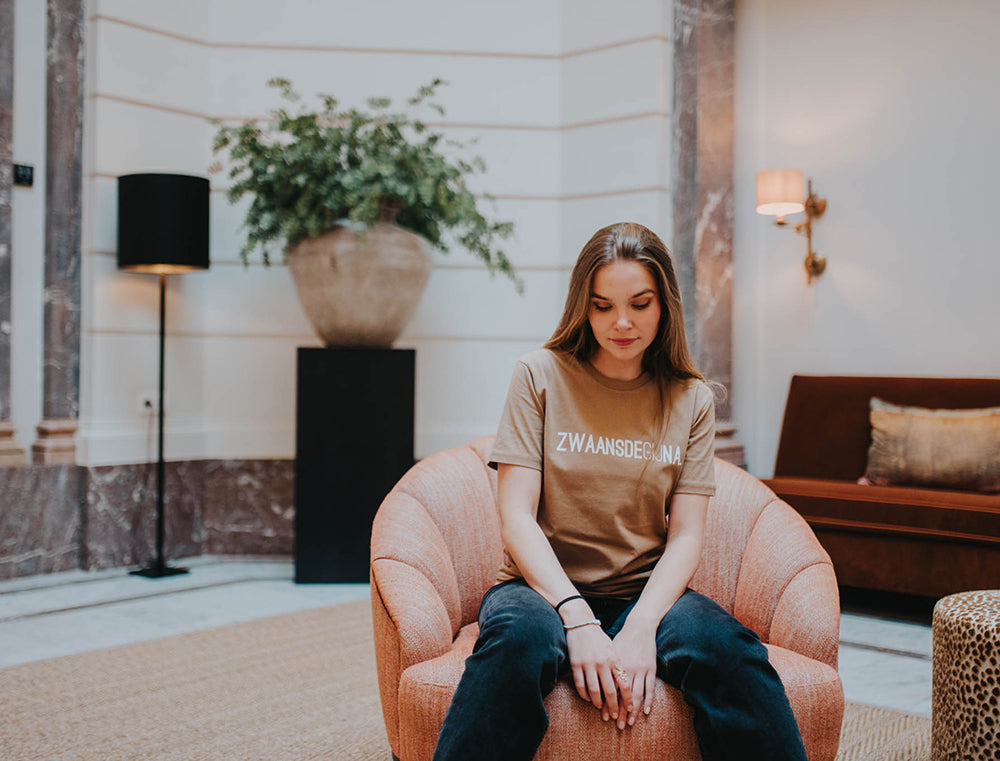Vrouw met een bruine T-shirt met opdruk ZWAANSDEGIJNA.