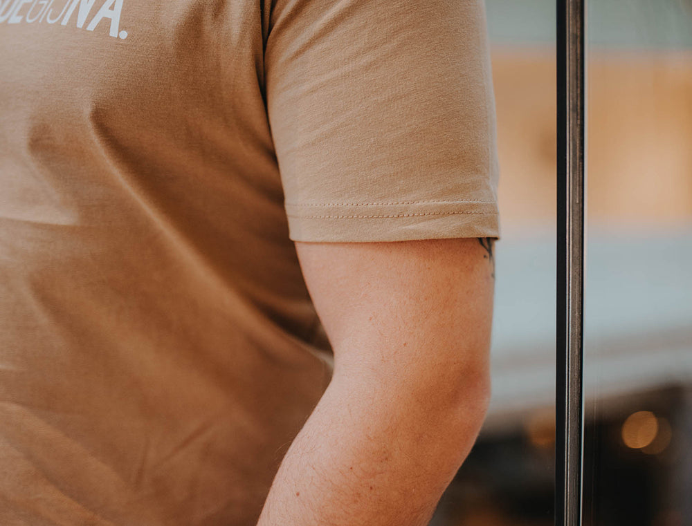 Close-up van de mouw van een bruine T-shirt.