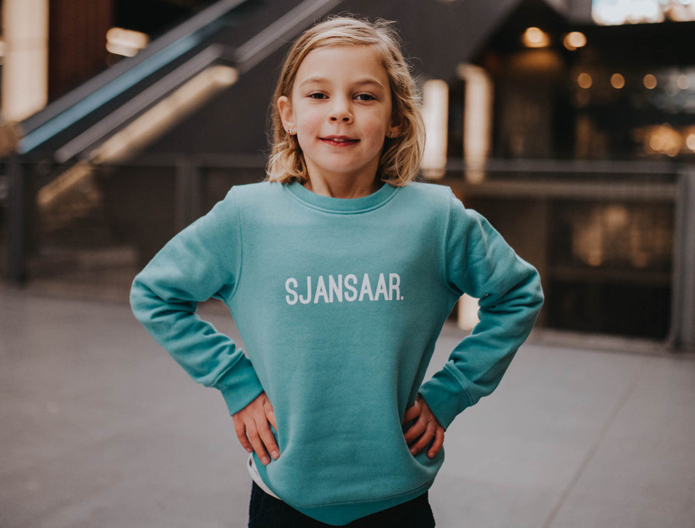 Meisje met een blauw-groene trui met opdruk SJANSAAR.