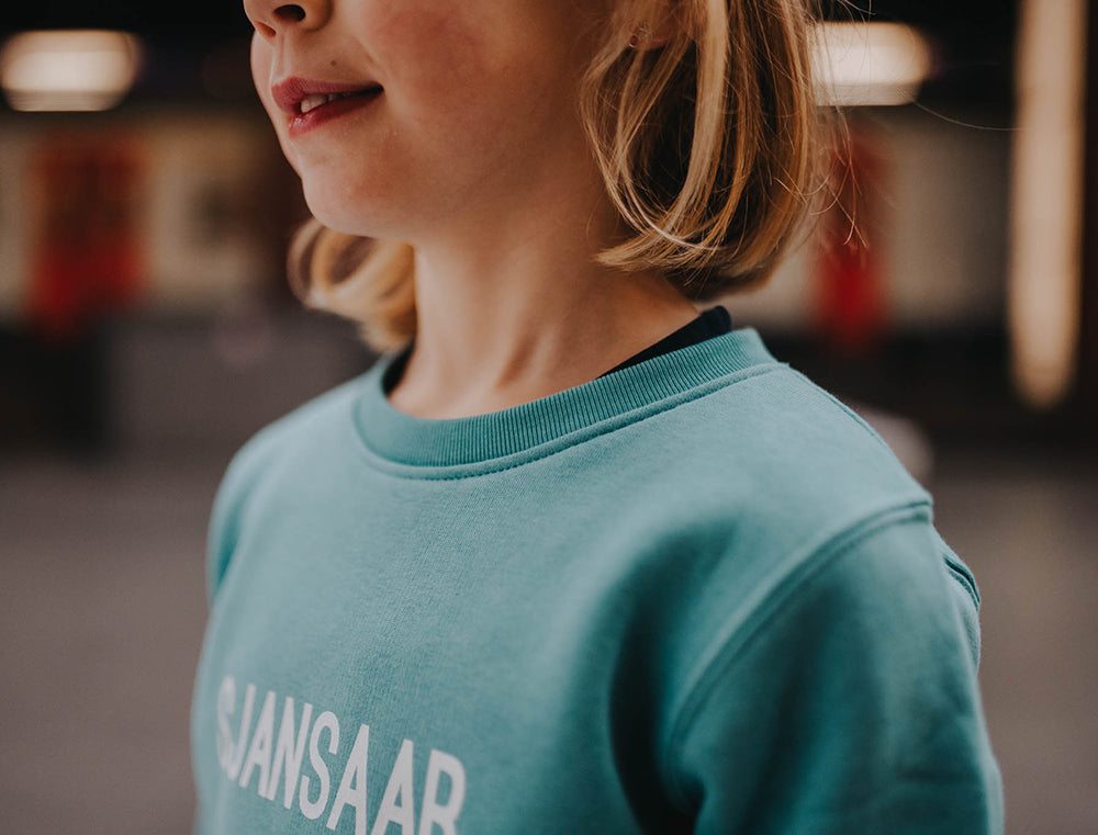 Close-up van een blauw-groene trui.