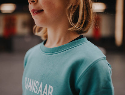 Close-up van een blauw-groene trui.
