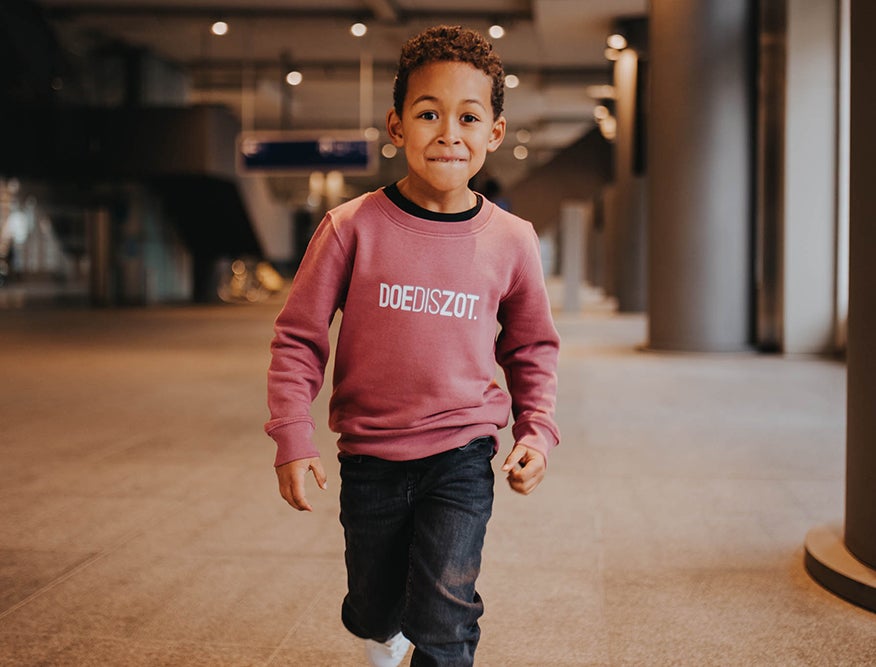 Jongen met een bordeaux trui met opdruk DOEDISZOT.