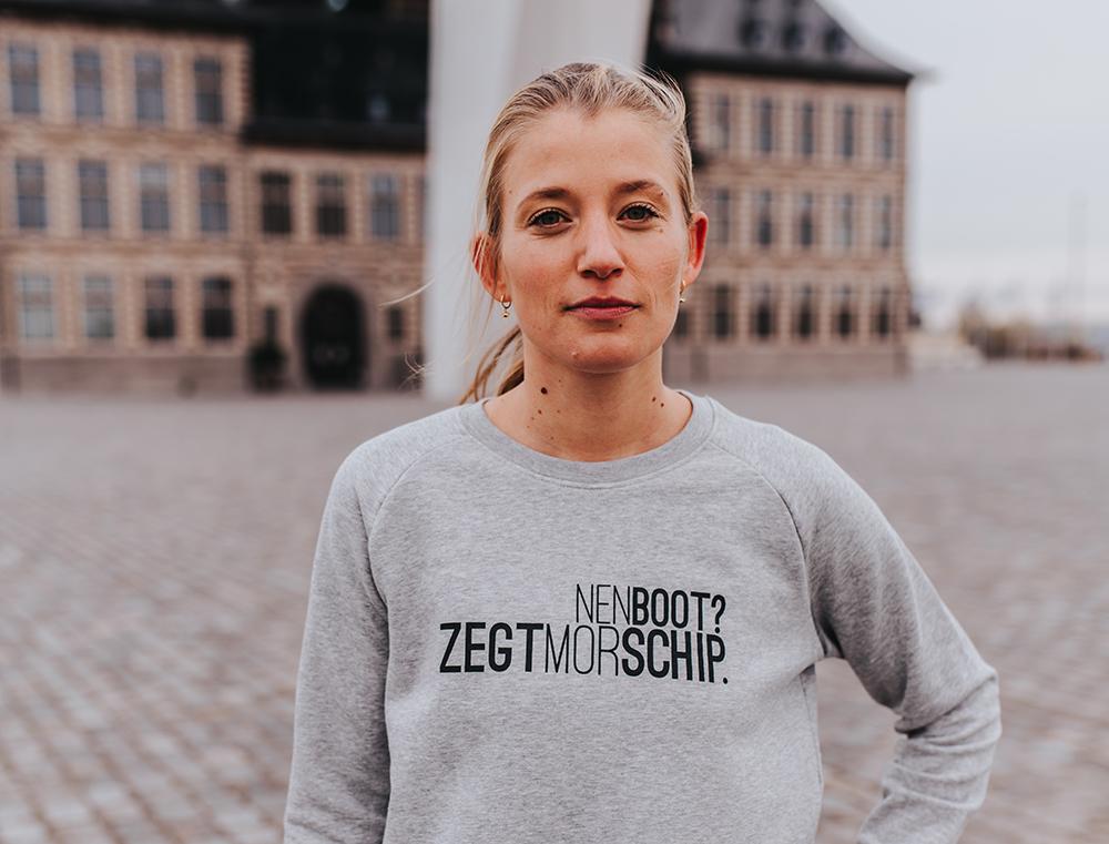 Vrouw met grijze trui met opschrift NENBOOT?ZEGTMORSCHIP.