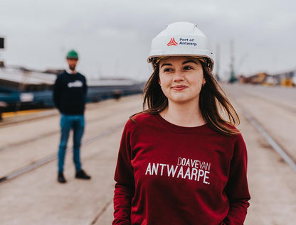 Vrouw met bordeaux trui met opschrift DOAVEVANANTWAARPE.