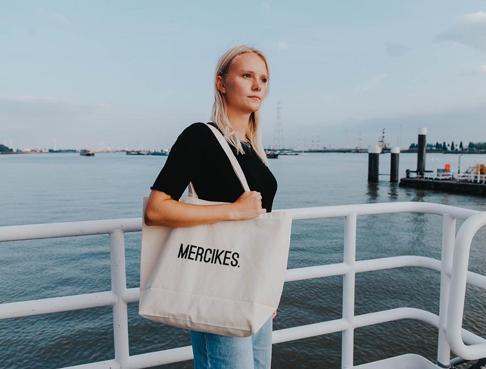 Vrouw met een totebag met opdruk MERCIKES.
