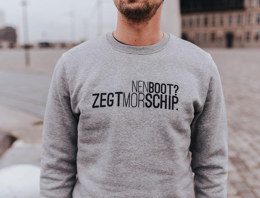 Man met grijze trui met opschrift NENBOOT?ZEGTMORSCHIP.