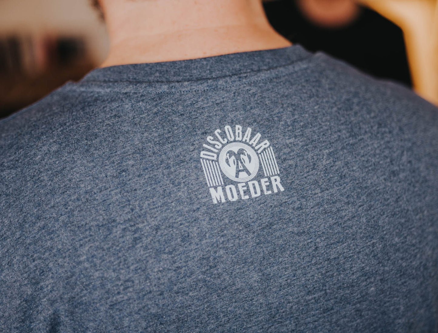 Close-up van het logo van Discobaar a moeder op een donkerblauwe T-shirt.